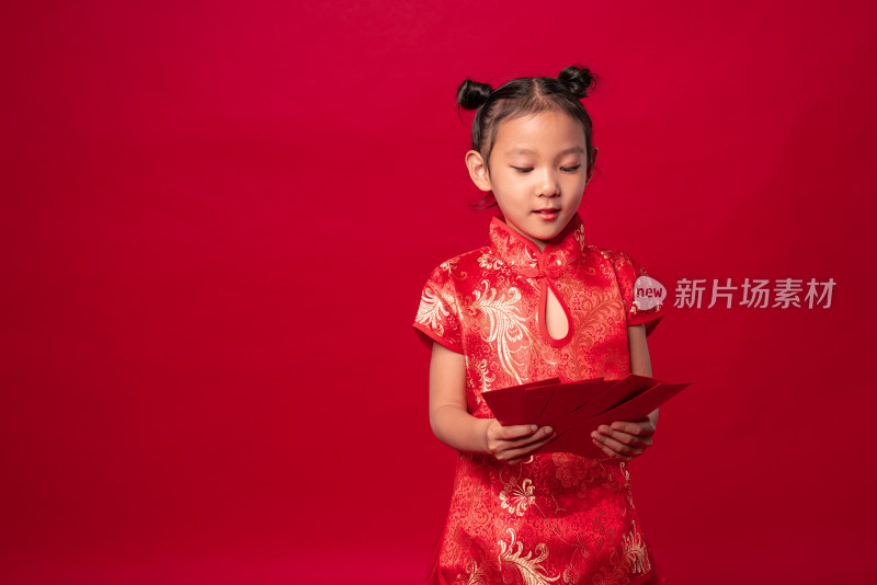 红色背景前穿旗袍拿着多个红包的中国女孩