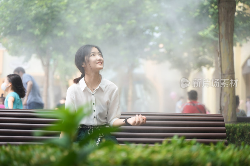 少女坐在公园的长椅上雾气喷雾朦胧