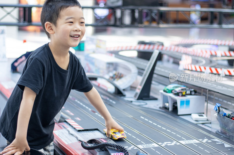 一个小男孩在游戏厅玩赛车玩具