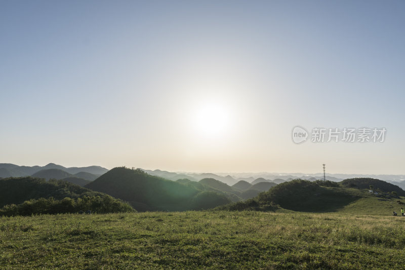 阳光下的广袤草原与起伏山脉的美景