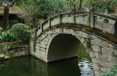 石桥横跨水面，周围绿树环绕的景色