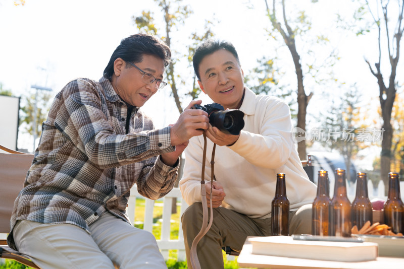 两个老年男人坐在露营地看数码相机