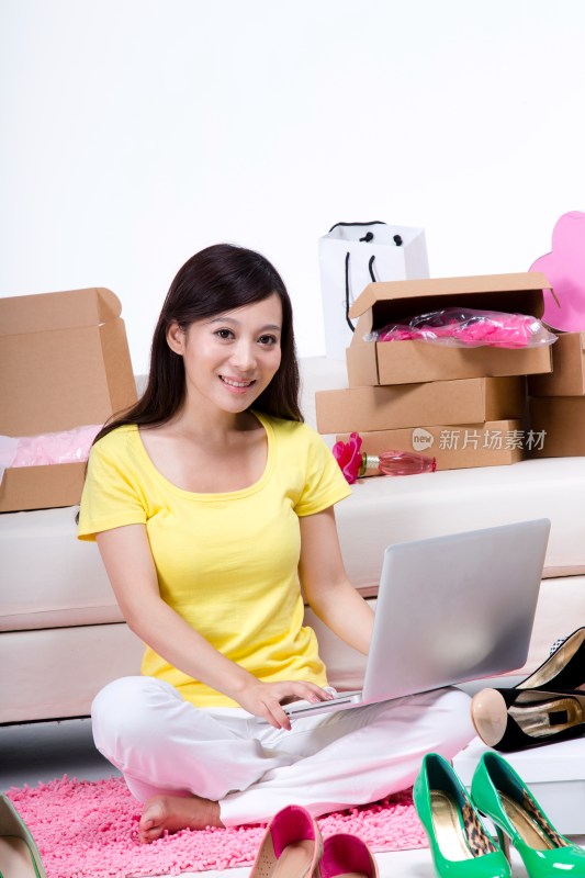 棚拍年轻女人坐在地上使用笔记本电脑上网购物