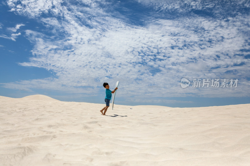 在白沙漠上玩滑板的中国小男孩
