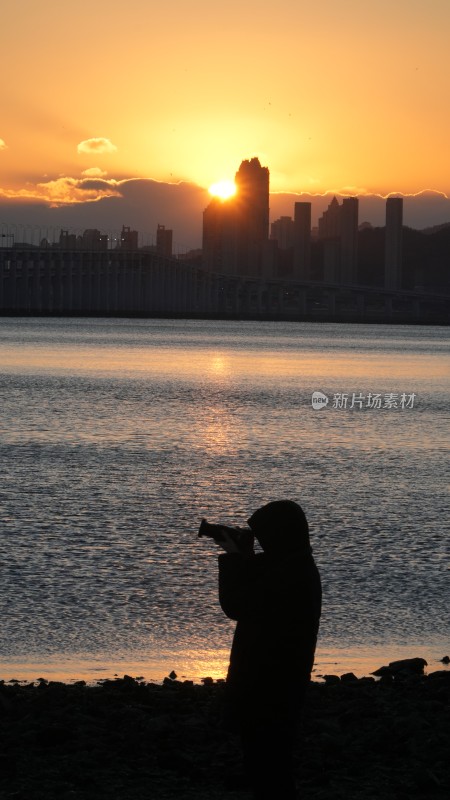 摄影师拍摄水边城市日出剪影