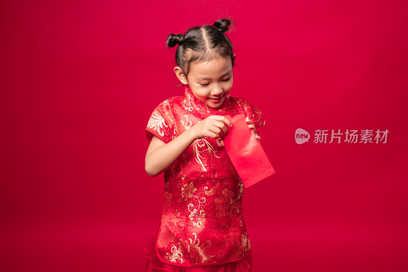 站在红色背景前穿旗袍拆开红包的中国女孩