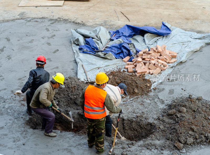 建筑工地上几个合作挖坑的建筑工人