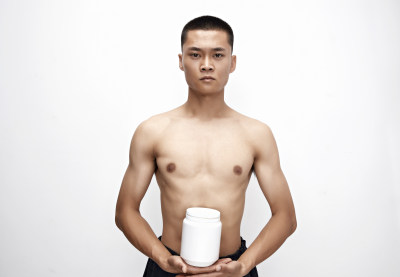 手持蛋白粉的身材匀称肌肉扎实的亚洲男性