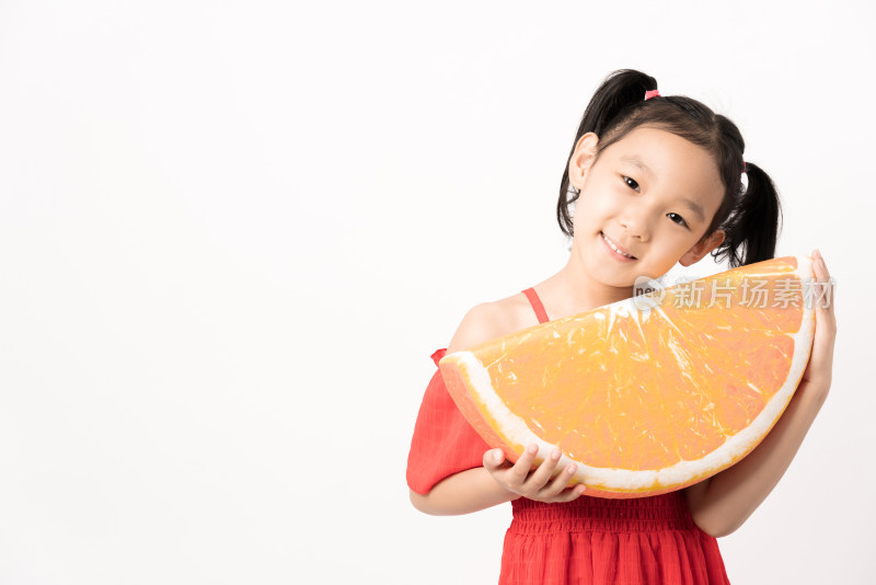 站在白色背景前拿着橙子玩具的女孩