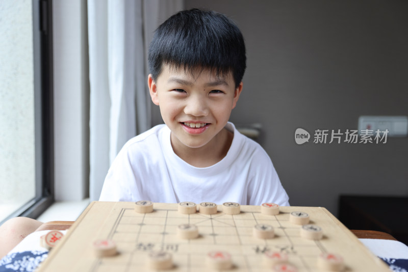 可爱的男孩在窗边下中国象棋