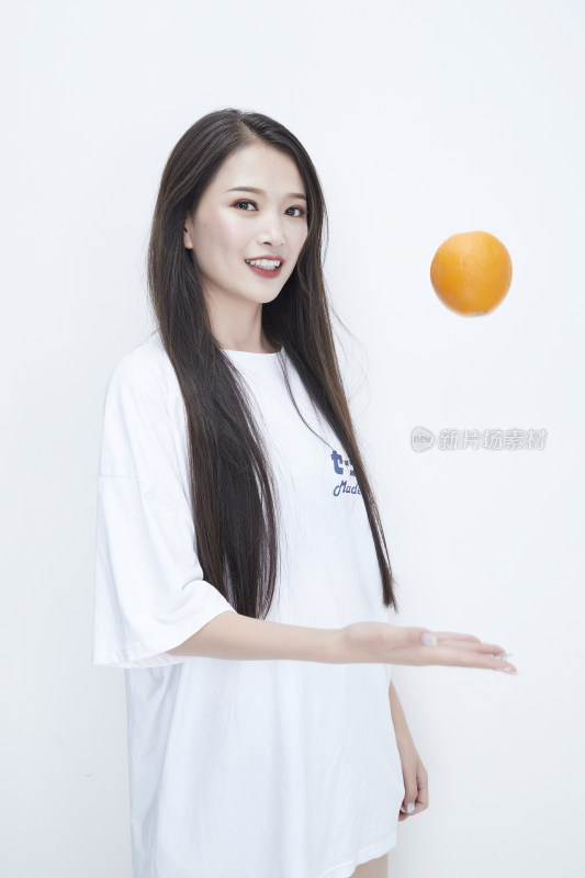 玩耍橙子穿白色长T血的亚洲可爱少女人像