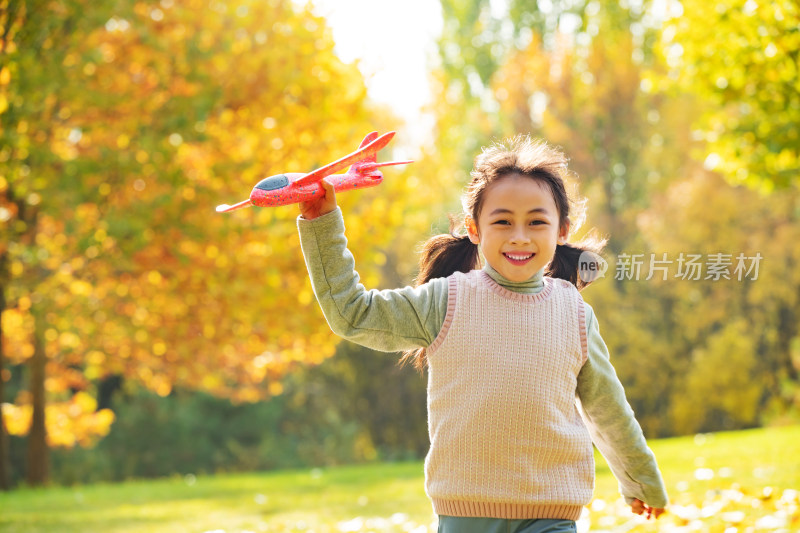 拿着玩具飞机在公园玩耍的小女孩