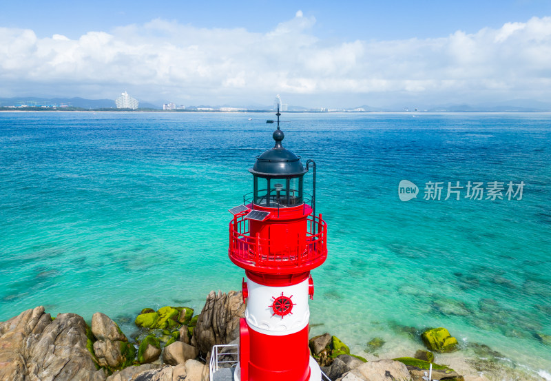 阳光下的海南三亚海岸线上礁石海浪花灯塔