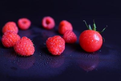 黑色背景下的树莓和小番茄特写镜头