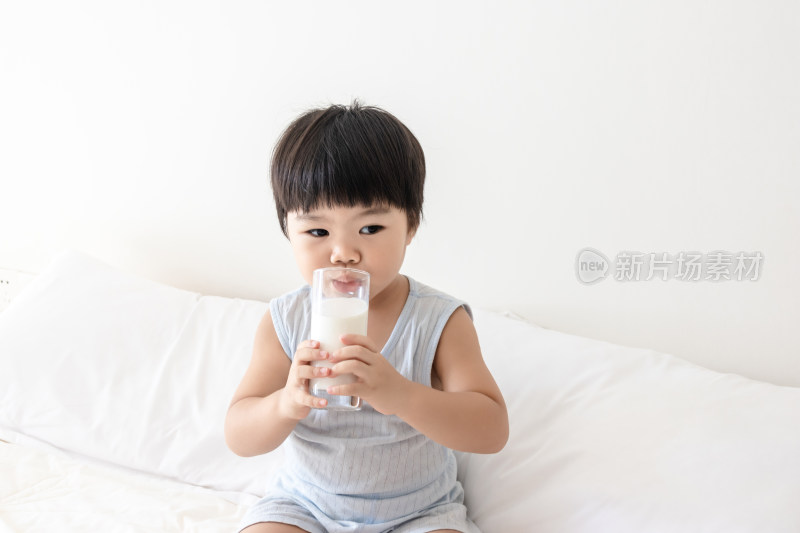卧室内一个小孩子在床上喝牛奶