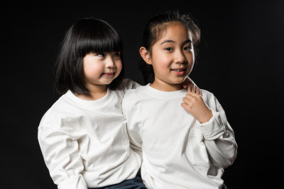 坐在黑背景前玩耍的两个亚裔女孩