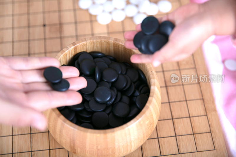 一只小手正把棋子放入棋盒中