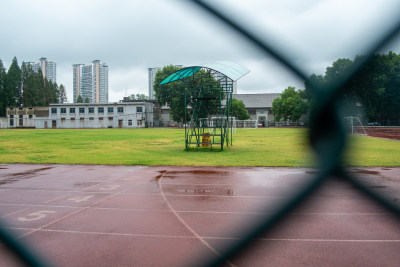 雨中操场看台，背景是高楼和绿树