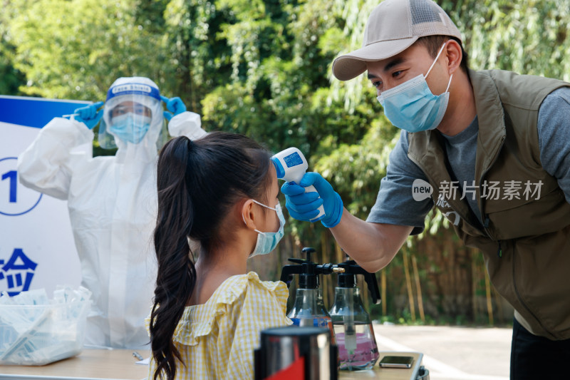 社区志愿者给小女孩测体温