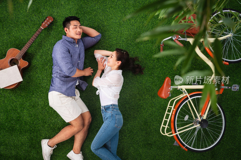 幸福的青年伴侣面对面躺在草地上