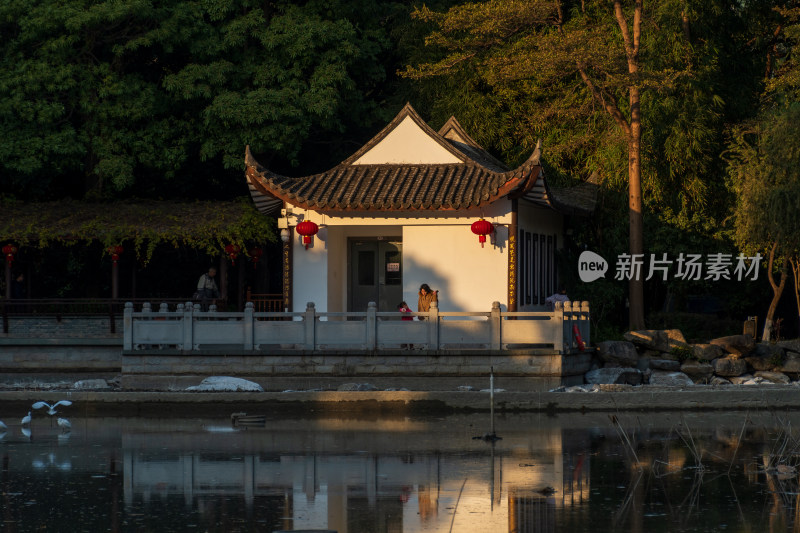 水边中式亭子旁有人闲坐的场景