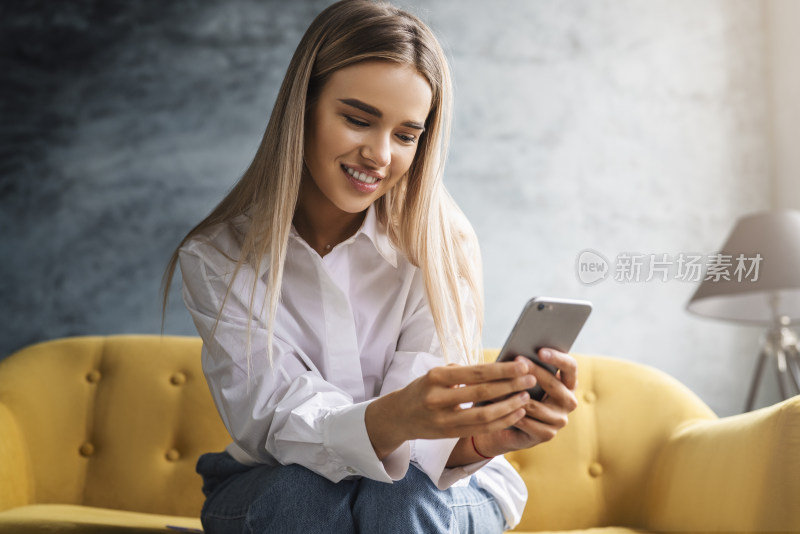 女子坐在沙发上使用手机