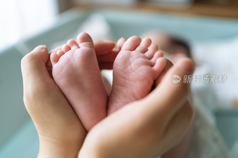 妈妈的大手捧着宝宝的小脚，形成一个爱心