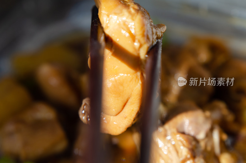 阳光下，用筷子夹起一块鸡肉肉块