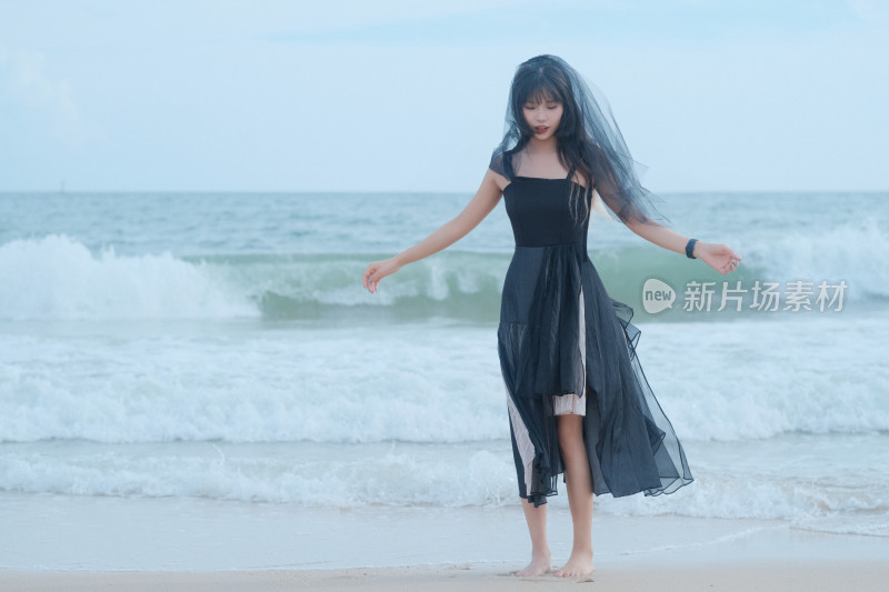 戴黑色头纱站在海边的女人