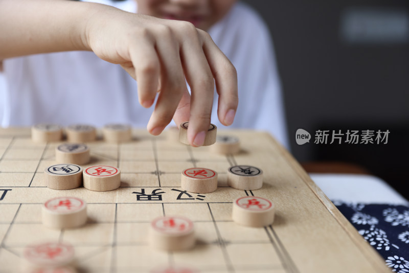 可爱的男孩在窗边下中国象棋