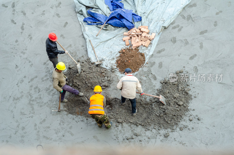 建筑工地上几个合作挖坑的建筑工人