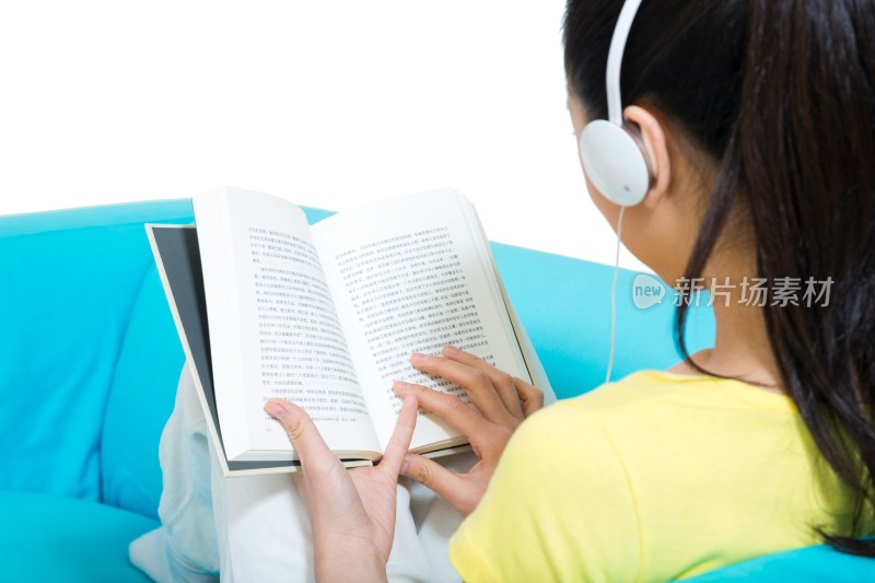 棚拍年轻女人坐在沙发上听着音乐看书