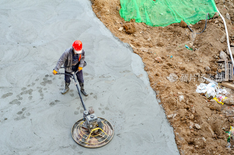 建筑工地上，工人使用路面抹平机平整路面