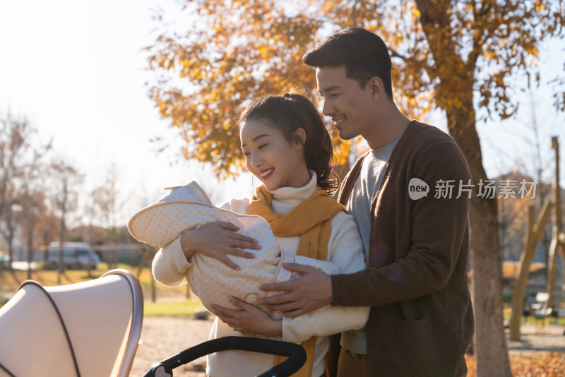 年轻夫妻推着婴儿车散步