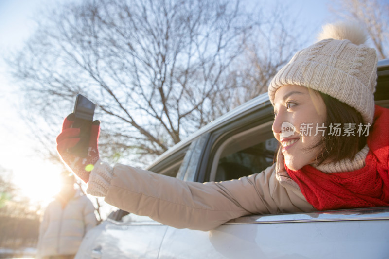 年轻女人坐在汽车里看手机