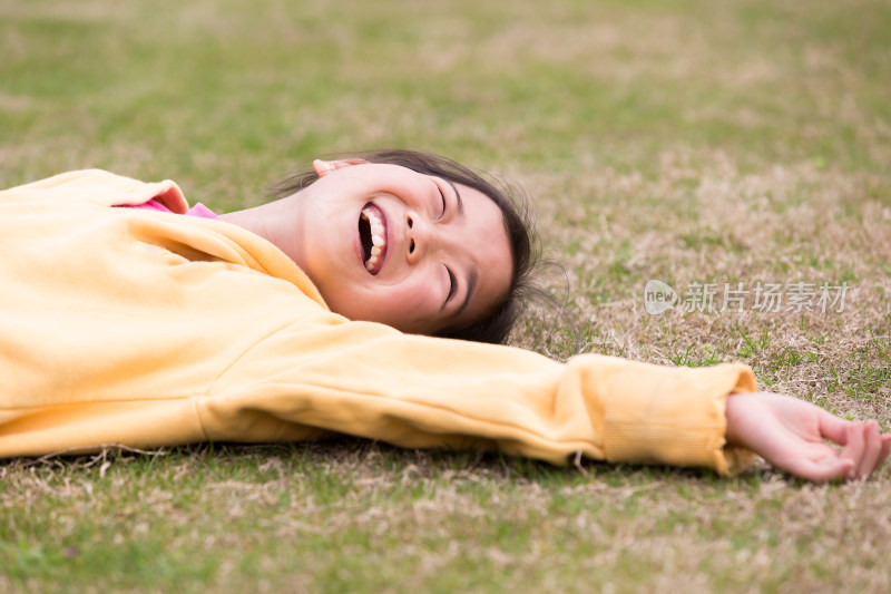 躺在草地上开心笑着的女孩