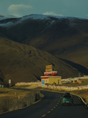 高原公路旁藏式建筑与行驶汽车