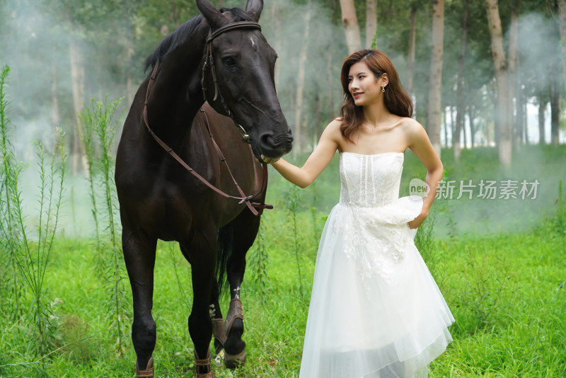 树林里漂亮的年轻女人牵着马