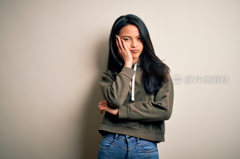 亚洲女性靠墙单手托腮表情苦恼