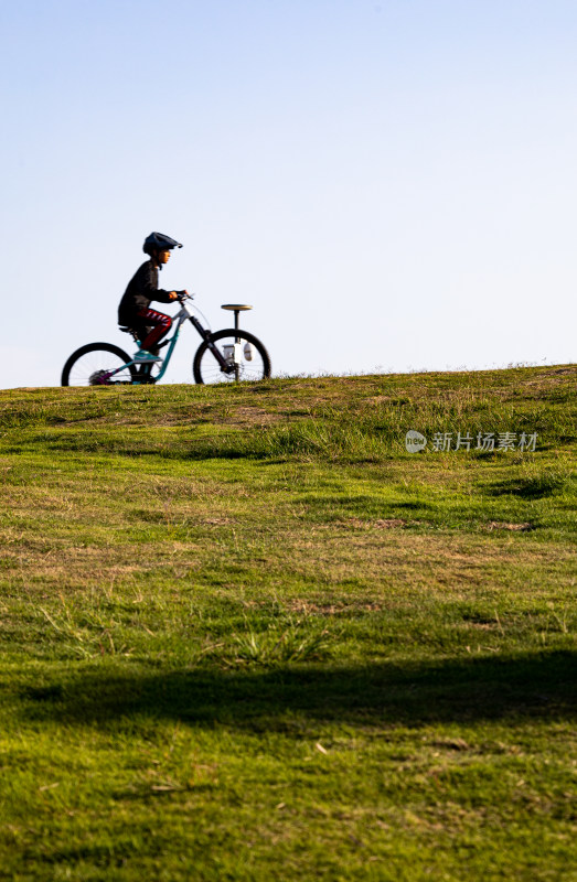 山东青岛海之恋公园海滨草坡上骑单车的少年