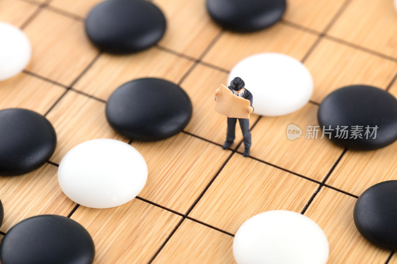 在棋盘棋子中间看书的人偶