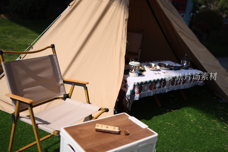 草地上的露营帐篷和空椅子和桌子