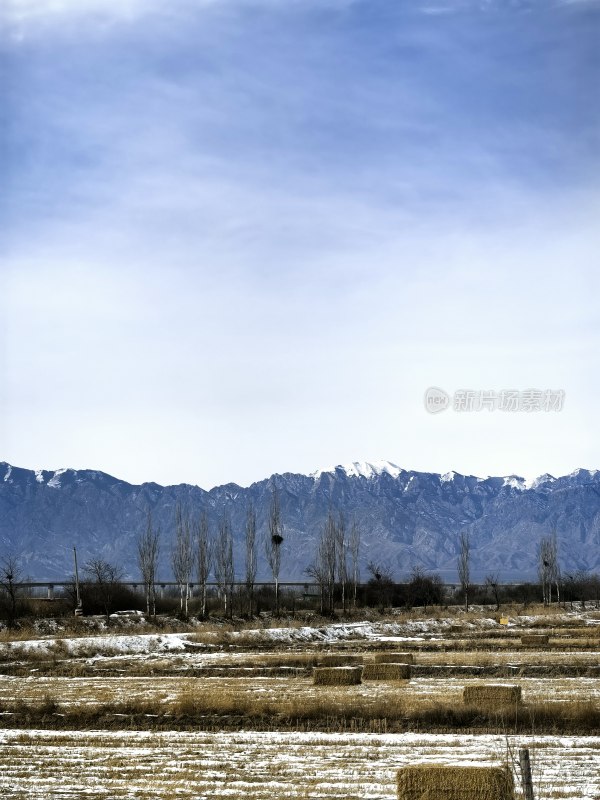 雪山下田野与干草堆风景