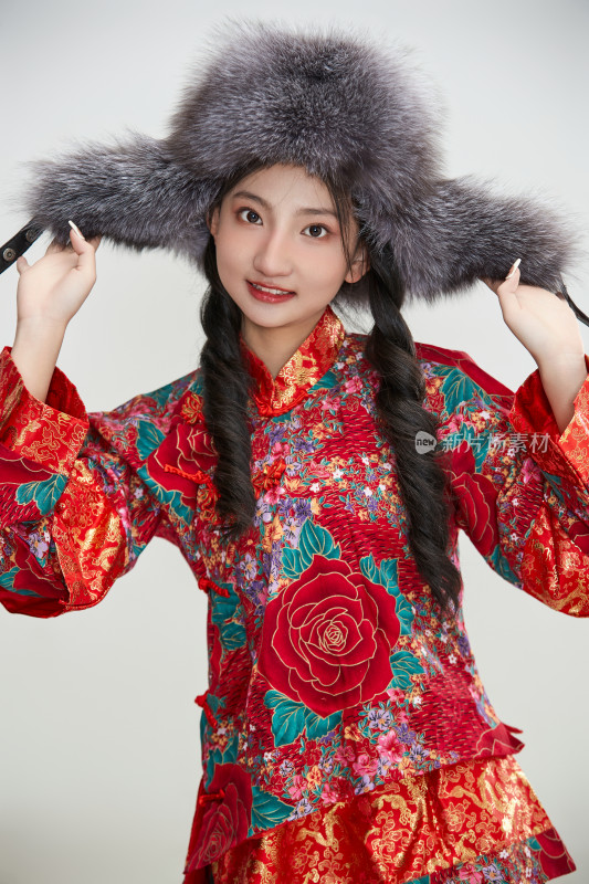 白色背景下穿中国传统服饰头戴绒帽的少女
