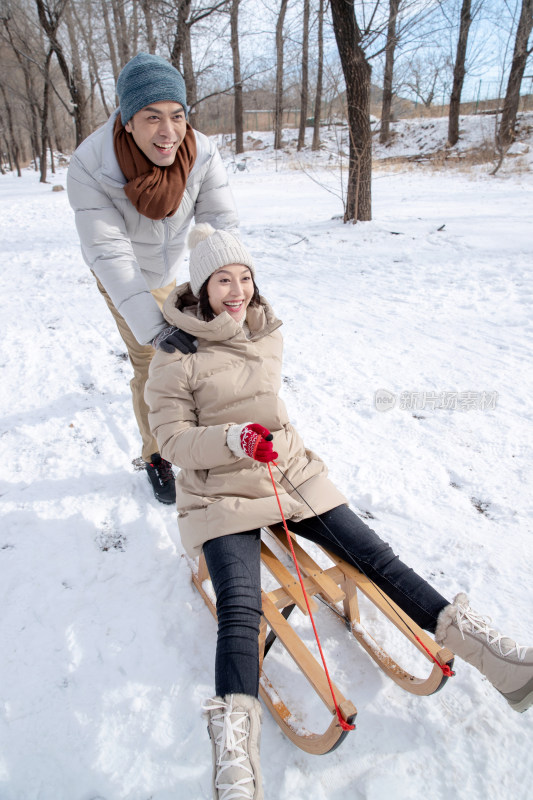 青年夫妇在雪地上玩雪橇