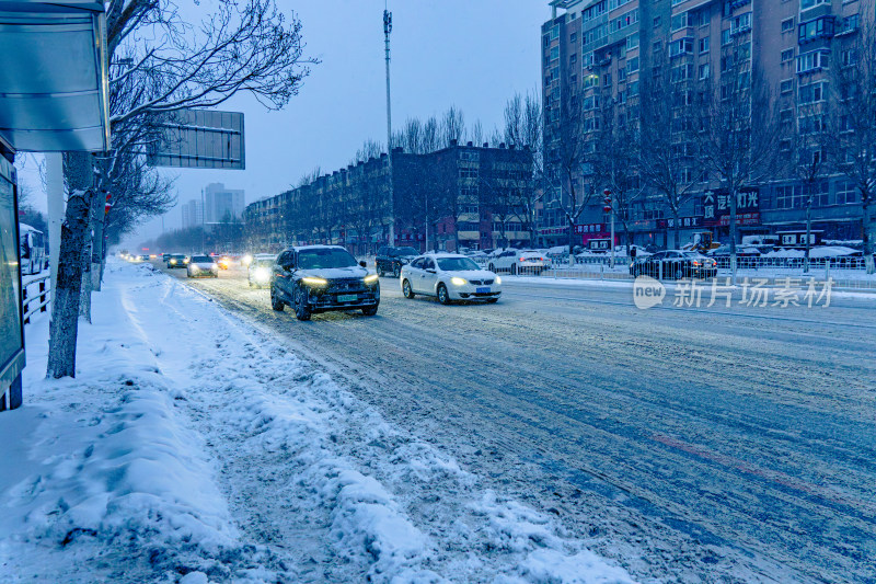 雪天夜晚亮灯的居民楼外景马路街道