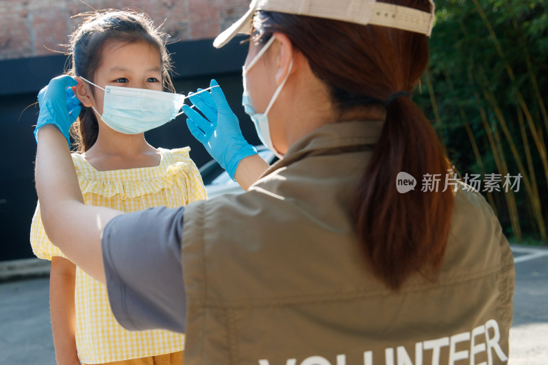 社区志愿者帮小女孩戴口罩