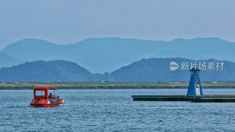 湖中小船与岸边灯塔的自然风景图