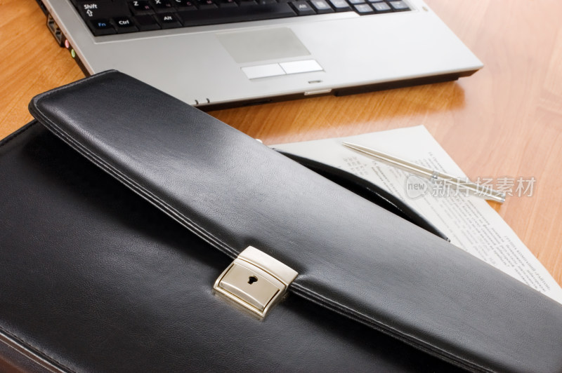 办公桌上的笔记本电脑与皮包