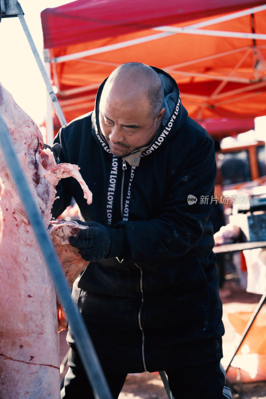 男子户外处理整只猪肉